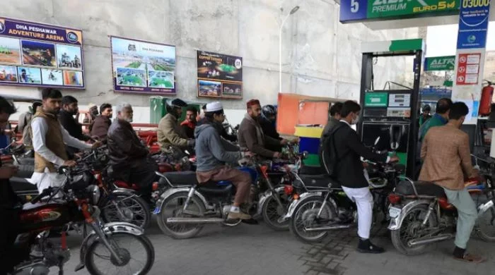 People wait for their turn to get fuel at a petrol station in Peshawar.