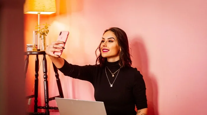 Influencer taking a selfie with a laptop, symbolizing Pakistan’s new 5% tax on digital content creators.